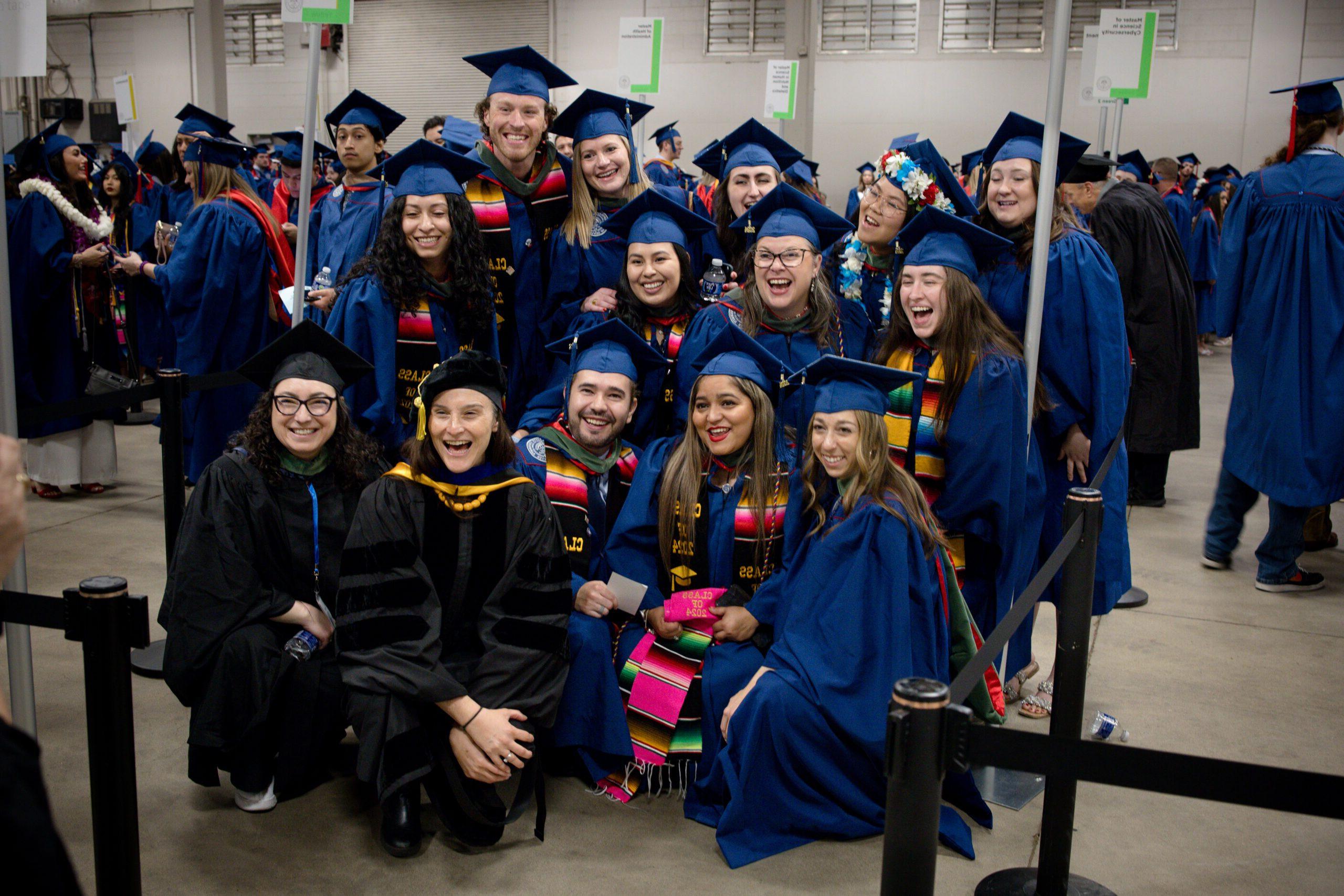 A group of graduates and Commencement marshals gather for a group photo.